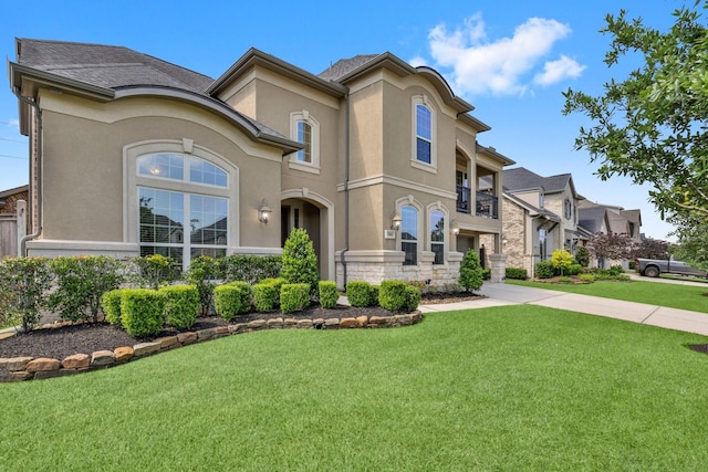 mediterranean / spanish house featuring stone siding, a front yard, and stucco siding