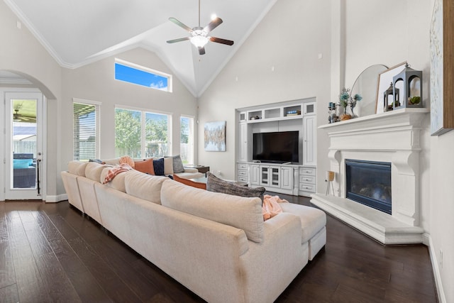 living room featuring a ceiling fan, high vaulted ceiling, baseboards, a glass covered fireplace, and dark wood-type flooring