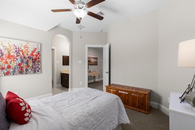 bedroom with connected bathroom, arched walkways, visible vents, and light carpet