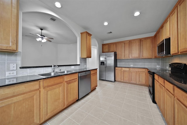kitchen featuring a ceiling fan, backsplash, appliances with stainless steel finishes, arched walkways, and a sink