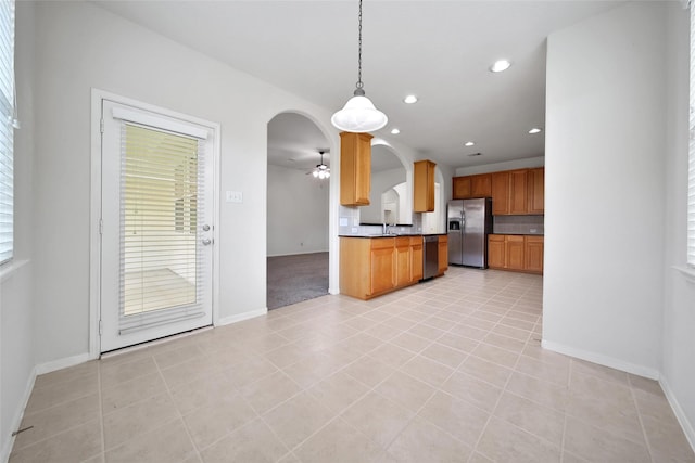 kitchen featuring stainless steel appliances, arched walkways, baseboards, and tasteful backsplash