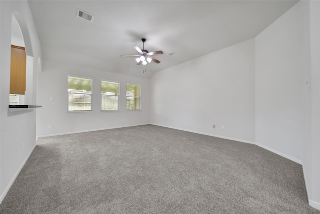 carpeted spare room featuring baseboards, ceiling fan, arched walkways, and visible vents