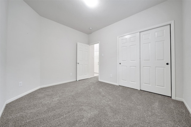 unfurnished bedroom with baseboards, carpet, and a closet