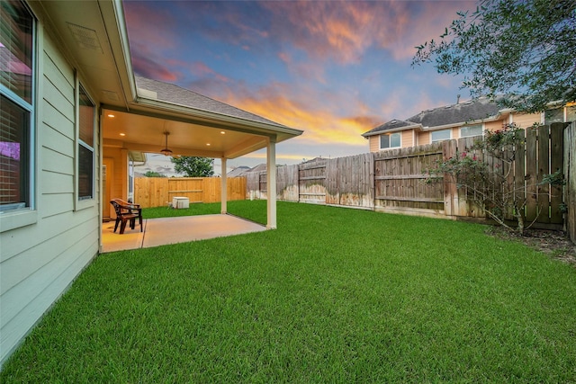 yard at dusk with a patio and a fenced backyard