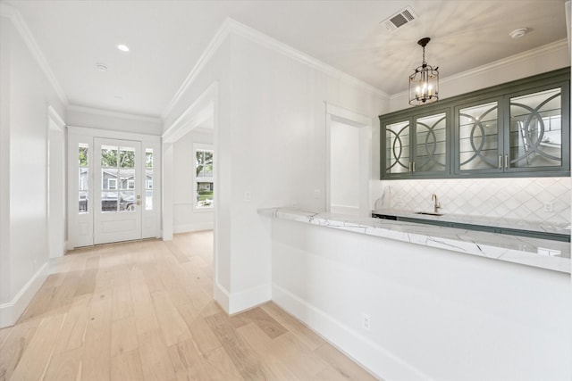 entryway featuring a chandelier, light wood-type flooring, baseboards, and crown molding