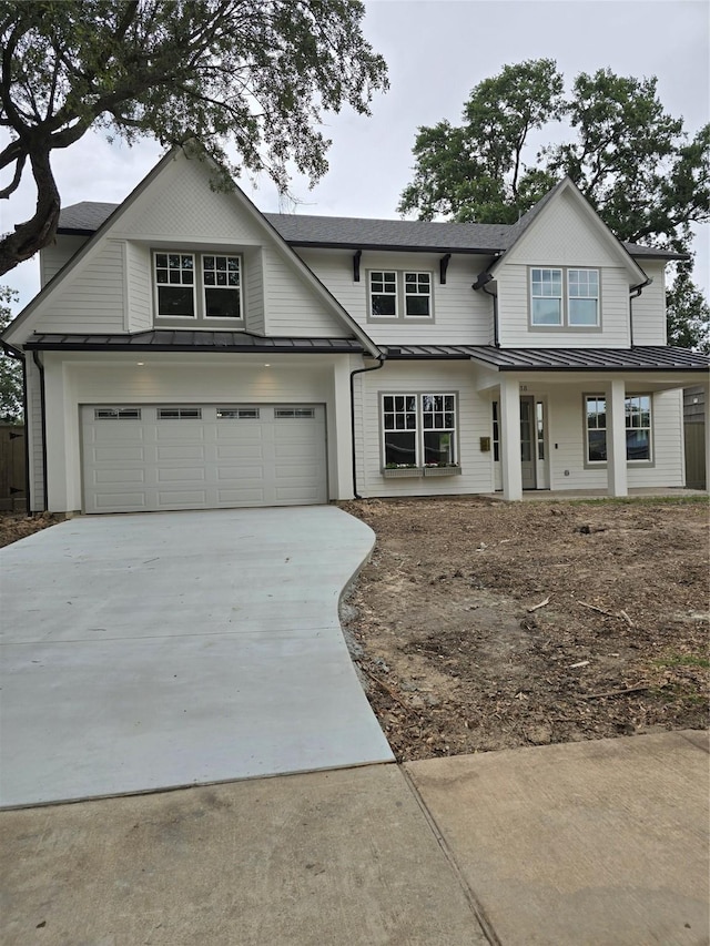 view of front of house with a standing seam roof, concrete driveway, metal roof, and a shingled roof