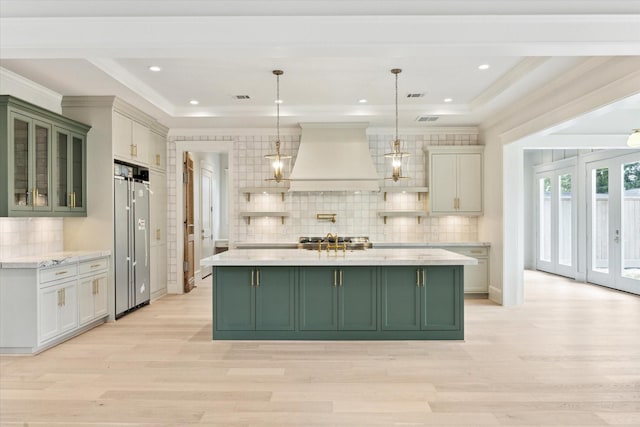 kitchen featuring green cabinets, custom range hood, light wood-style floors, backsplash, and crown molding
