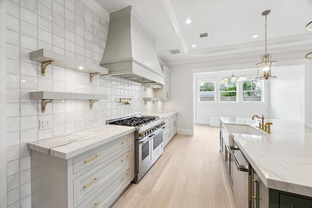 kitchen with appliances with stainless steel finishes, premium range hood, open shelves, light wood-style flooring, and ornamental molding