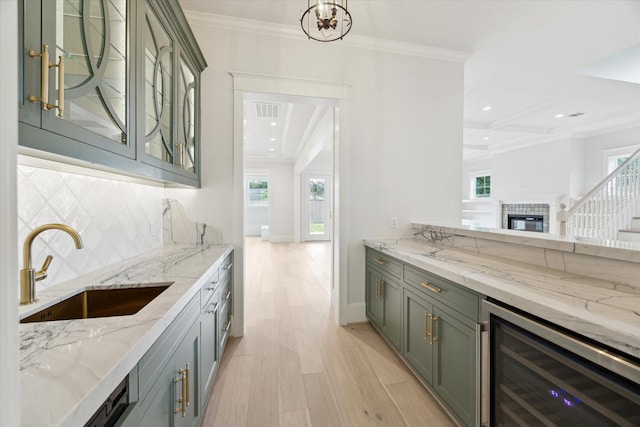 bar area featuring wine cooler, a sink, light wood-style floors, tasteful backsplash, and crown molding