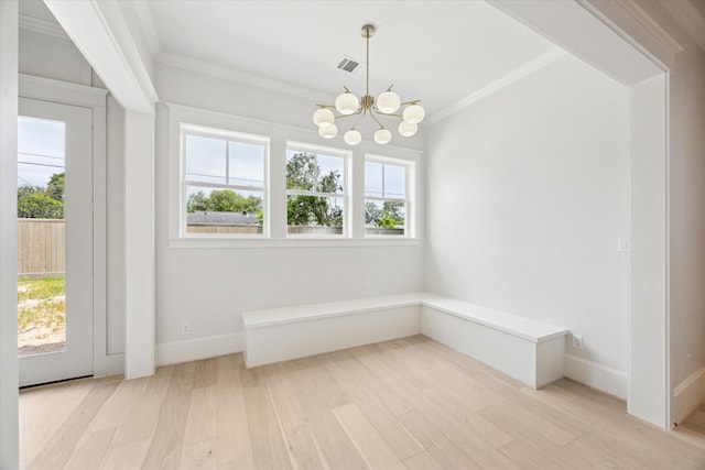 unfurnished dining area featuring a chandelier, light wood-style floors, healthy amount of natural light, crown molding, and baseboards