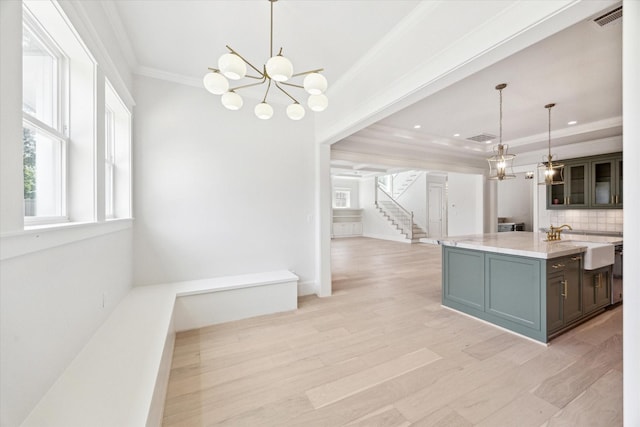 kitchen with a sink, crown molding, a chandelier, decorative light fixtures, and decorative backsplash
