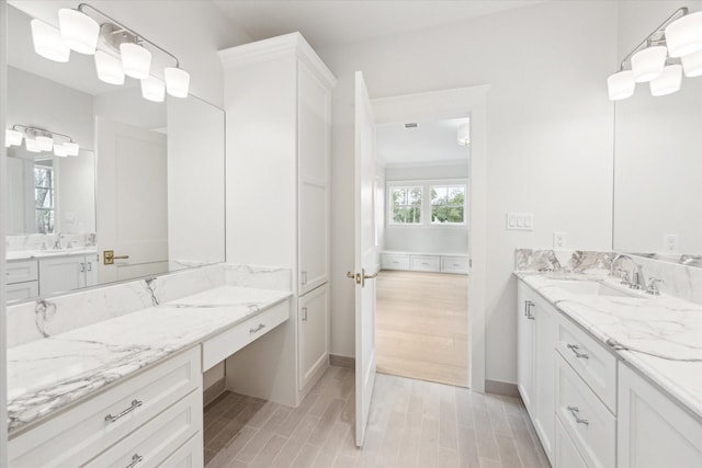 full bath featuring wood finished floors, baseboards, and two vanities