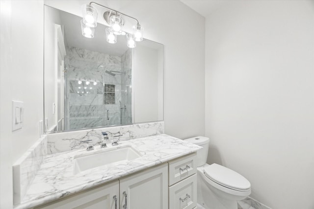 bathroom featuring a marble finish shower, toilet, and vanity