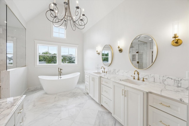 full bath featuring marble tiled flooring, a walk in shower, a chandelier, double vanity, and a freestanding tub