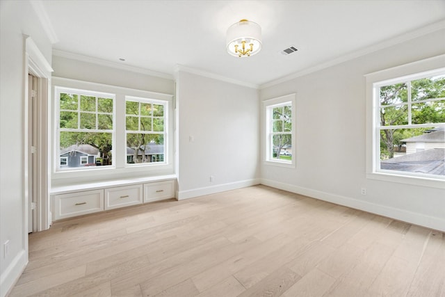 spare room with light wood-style floors, a chandelier, ornamental molding, and baseboards