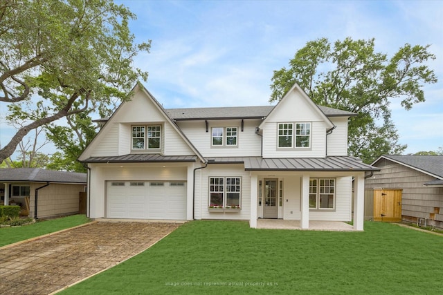 view of front facade featuring a standing seam roof, driveway, a garage, and metal roof