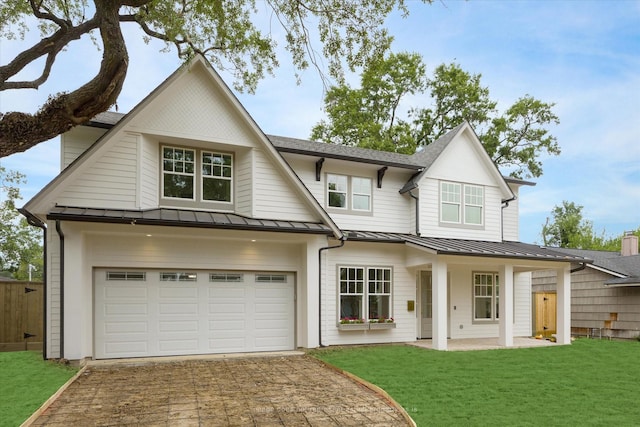 view of front of house with a standing seam roof, driveway, a front yard, and a shingled roof