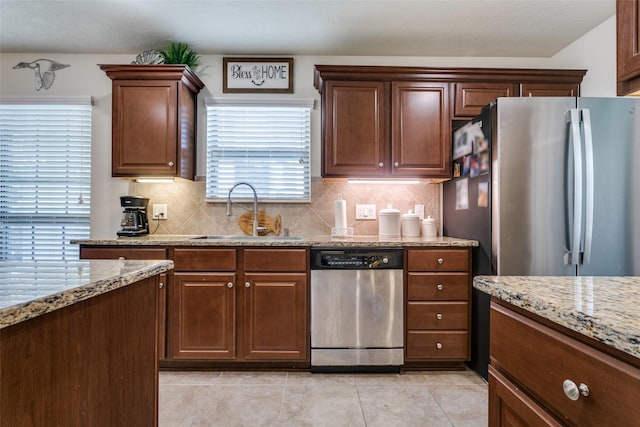 2017 Amado Ln, League City, TX 77573 - kitchen featuring appliances with stainless steel finishes, a sink, light tile patterned floors, and decorative backsplash