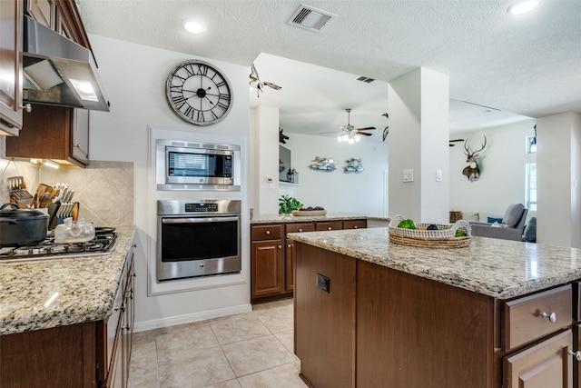 2017 Amado Ln, League City, TX 77573 - kitchen featuring stainless steel appliances, exhaust hood, a center island, light stone counters, and a textured ceiling