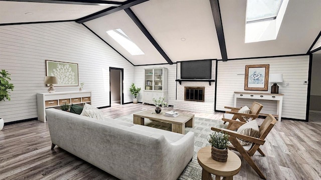 living area with a skylight, wood walls, baseboards, and wood finished floors