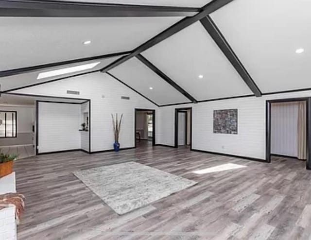 unfurnished living room with wood finished floors, recessed lighting, and brick wall