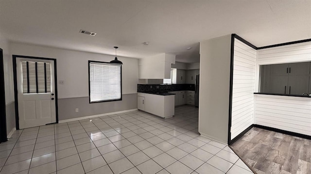 kitchen featuring light tile patterned floors, baseboards, dark countertops, and freestanding refrigerator
