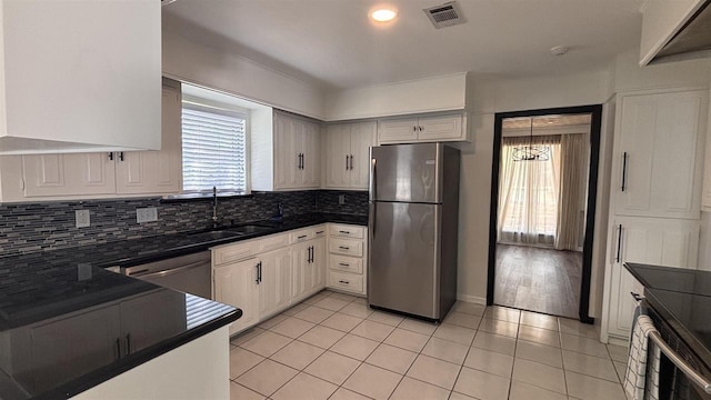 kitchen with stainless steel appliances, dark countertops, decorative backsplash, a sink, and light tile patterned flooring