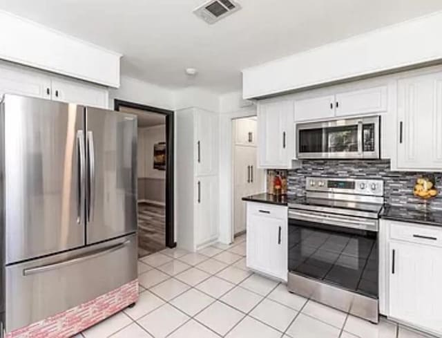 kitchen with stainless steel appliances, dark countertops, decorative backsplash, and white cabinetry