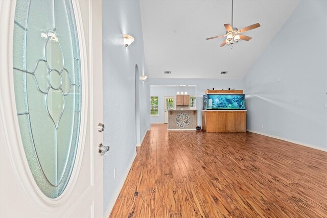 foyer entrance with ceiling fan, light wood finished floors, high vaulted ceiling, baseboards, and visible vents