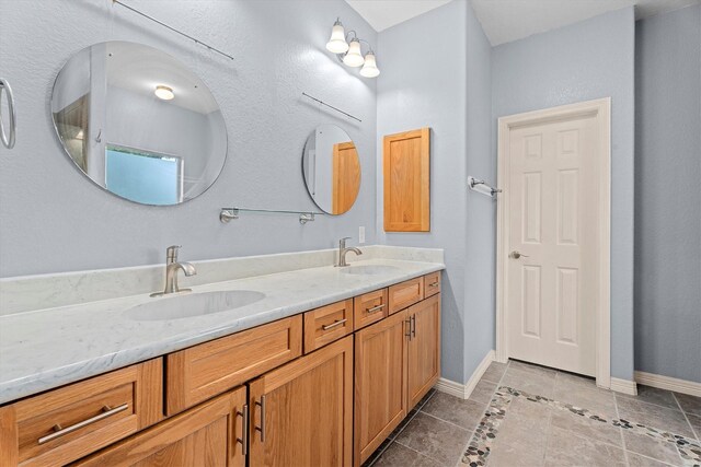 bathroom featuring double vanity, a sink, baseboards, and tile patterned flooring