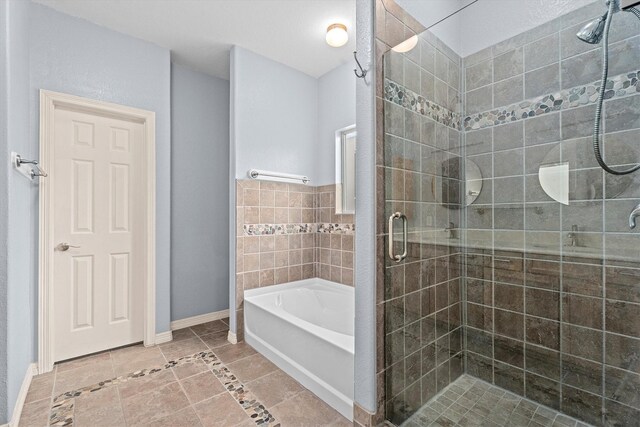 bathroom featuring tile patterned floors, a shower stall, baseboards, and a garden tub