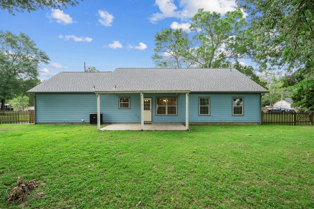 rear view of property with central air condition unit, a lawn, a fenced backyard, and a patio area