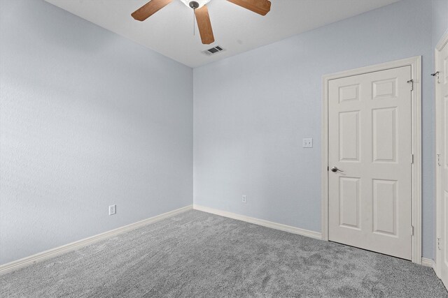 carpeted spare room featuring ceiling fan, visible vents, and baseboards