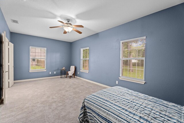 carpeted bedroom featuring a ceiling fan, baseboards, and visible vents