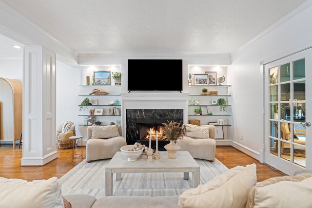 living room featuring a textured ceiling, ornamental molding, wood finished floors, and a high end fireplace
