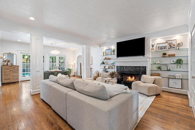 living area with a premium fireplace, a textured ceiling, recessed lighting, and wood finished floors