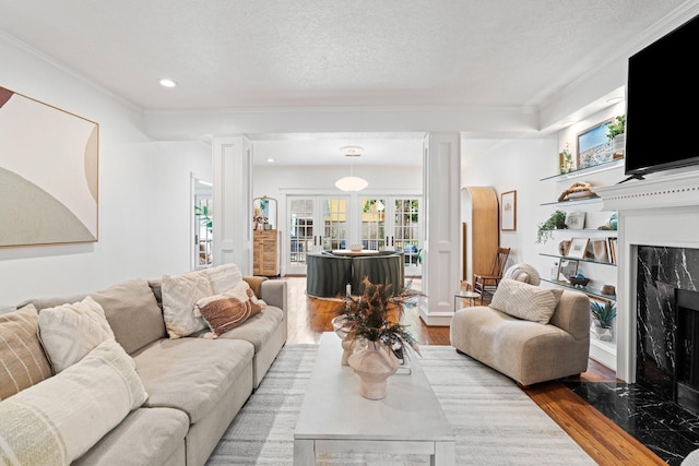 living room with a fireplace, wood finished floors, ornate columns, ornamental molding, and recessed lighting
