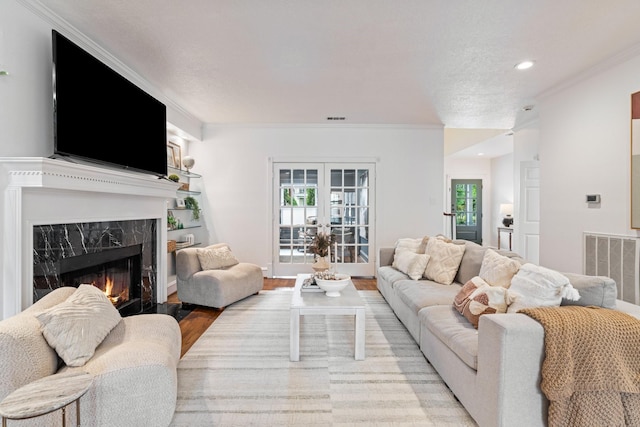 living room with a fireplace, light wood-style floors, recessed lighting, visible vents, and ornamental molding