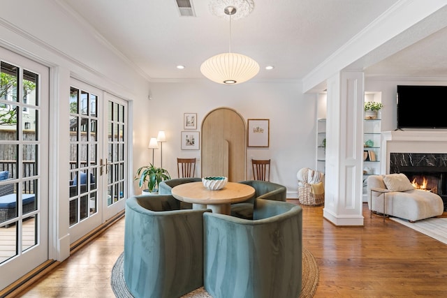dining space featuring ornamental molding, a premium fireplace, wood finished floors, and visible vents