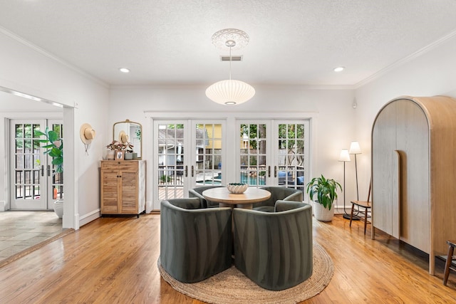 dining room featuring ornamental molding, french doors, light wood finished floors, and visible vents