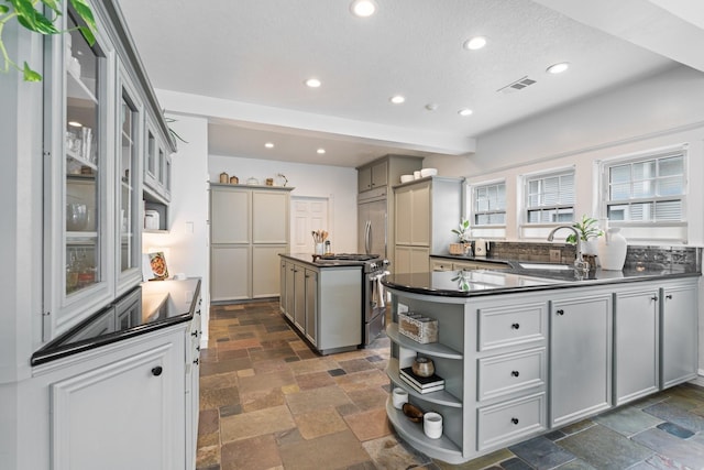 kitchen featuring open shelves, gray cabinetry, dark countertops, and a center island