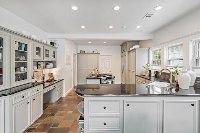 kitchen with visible vents, dark countertops, recessed lighting, a sink, and premium appliances