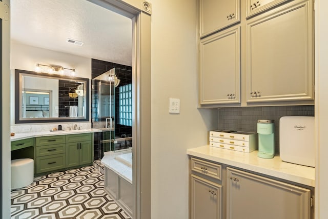 bathroom with backsplash, a textured ceiling, a bath, visible vents, and vanity