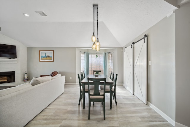 12858 Pelican Island Dr, Willis, TX 77318 - dining room with visible vents, lofted ceiling, baseboards, light wood-type flooring, and a barn door