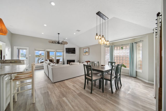 12858 Pelican Island Dr, Willis, TX 77318 - dining space featuring a chandelier, light wood-type flooring, lofted ceiling, and a fireplace