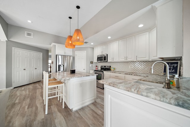 12858 Pelican Island Dr, Willis, TX 77318 - kitchen featuring backsplash, visible vents, appliances with stainless steel finishes, a sink, and light stone counters