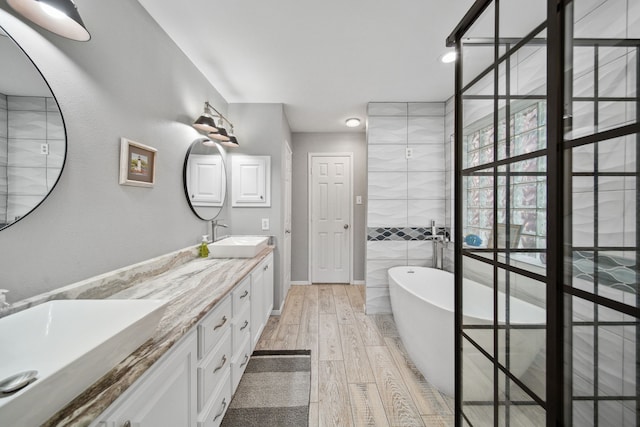 12858 Pelican Island Dr, Willis, TX 77318 - bathroom featuring double vanity, a soaking tub, a sink, and hardwood / wood-style flooring