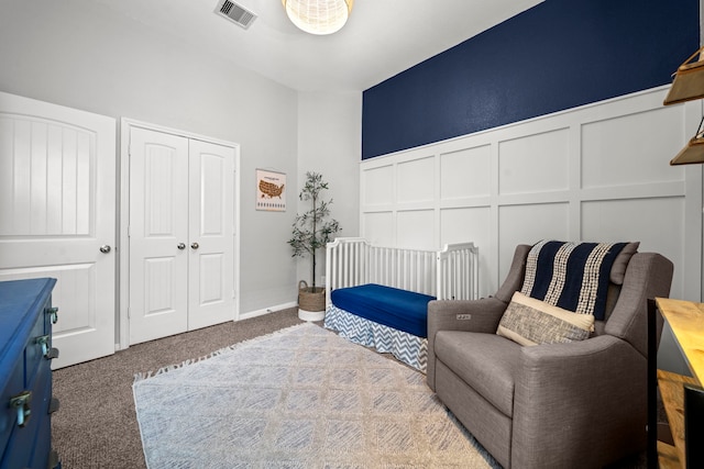 living area with visible vents, carpet flooring, wainscoting, and a decorative wall