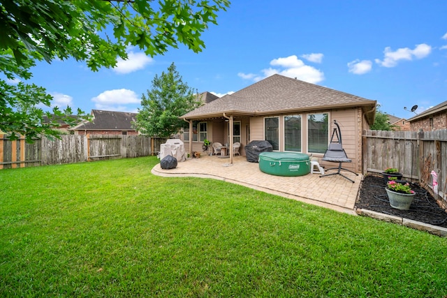 rear view of property with a fenced backyard, a yard, a patio area, and roof with shingles