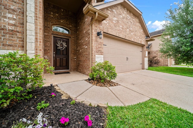 view of exterior entry with brick siding, a garage, and concrete driveway